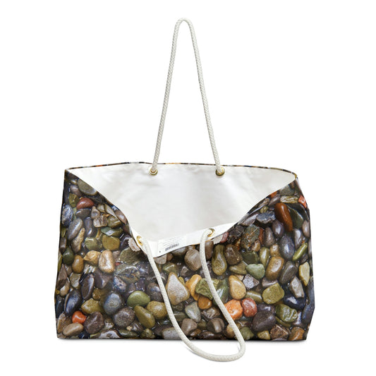 An open view of the beach bag with pebbles and stones design shows the cream colored interior lining.