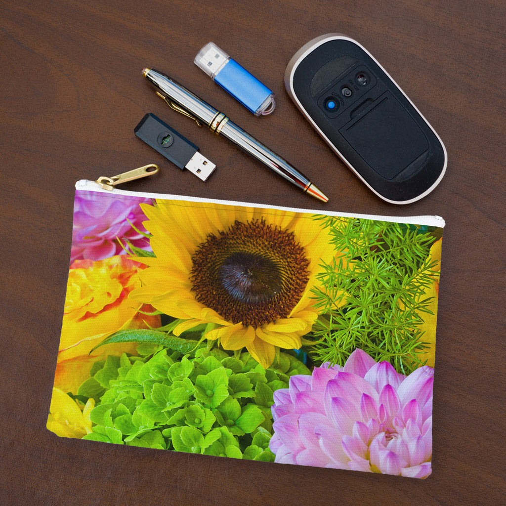 Small pouch with flower bouquet design lying flat on desktop with thumb drives, computer mouse and pen.