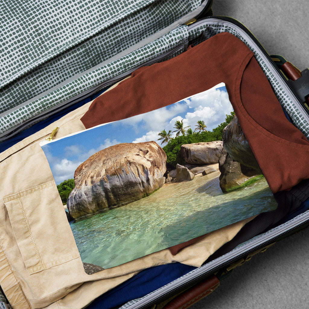 Large pouch with calm turquoise water design lying flat atop the contents of an open suitcase.