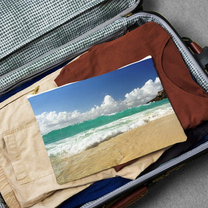Large pouch with crashing waves design lying flat atop the contents of an open suitcase.