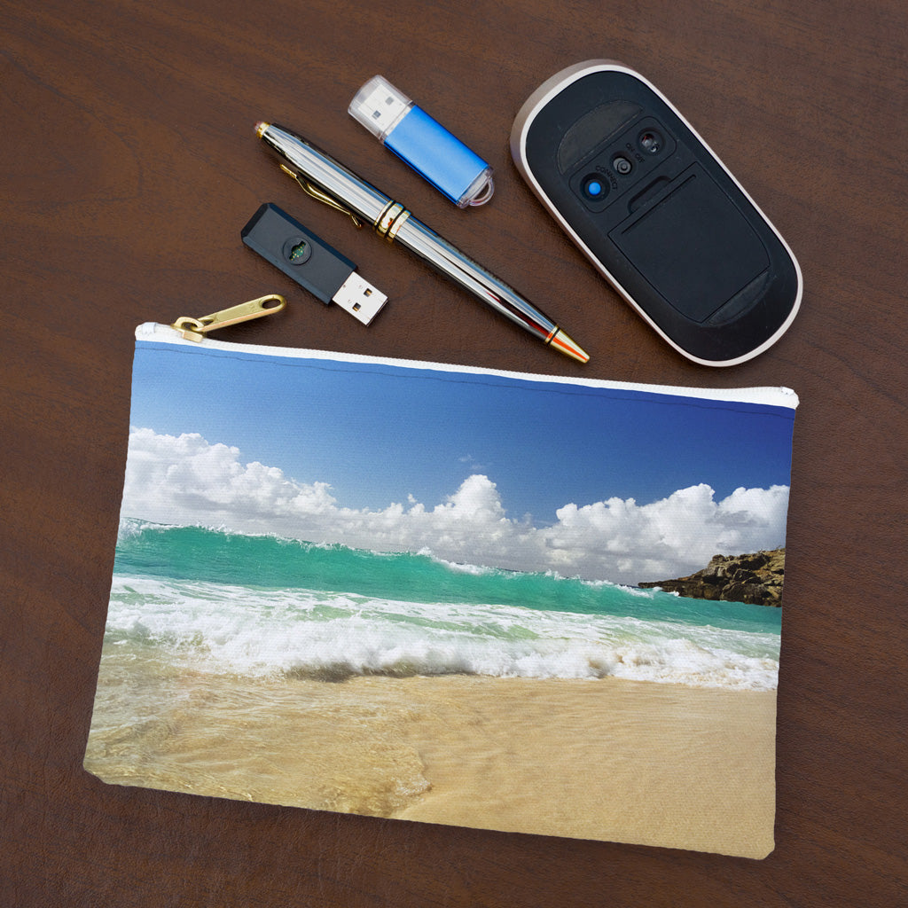 Small pouch with crashing waves design lying flat on desktop with thumb drives, computer mouse and pen.