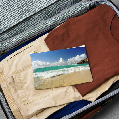 Small pouch with crashing waves design lying flat atop the contents of an open suitcase.