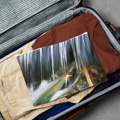 Large pouch with creek waterfall design lying flat atop the contents of an open suitcase.