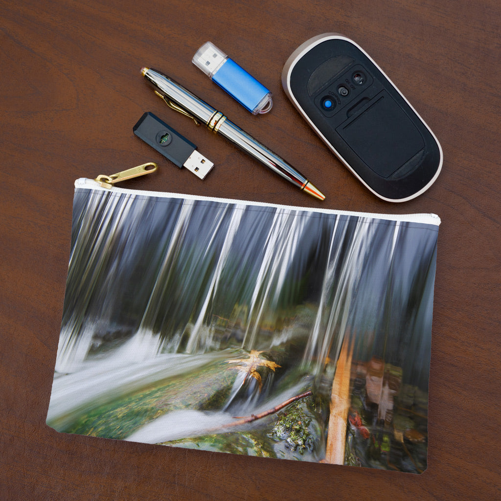 Small pouch with creek waterfall design lying flat on desktop with thumb drives, computer mouse and pen.