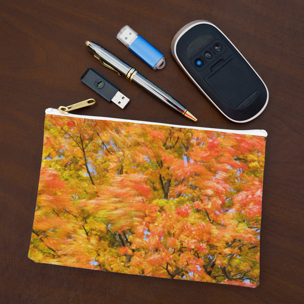 Small pouch with fall colored trees design lying flat on desktop with thumb drives, computer mouse and pen.