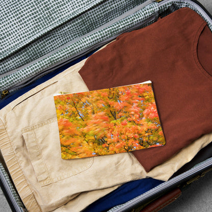 Small pouch with fall colored trees design lying flat atop the contents of an open suitcase.