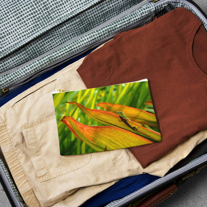 Small pouch with sunlit gecko design lying flat atop the contents of an open suitcase.