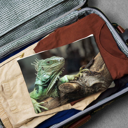 Large pouch with green iguana design lying flat atop the contents of an open suitcase.