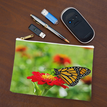 Small pouch with butterfly on flower design lying flat on desktop with thumb drives, computer mouse and pen.