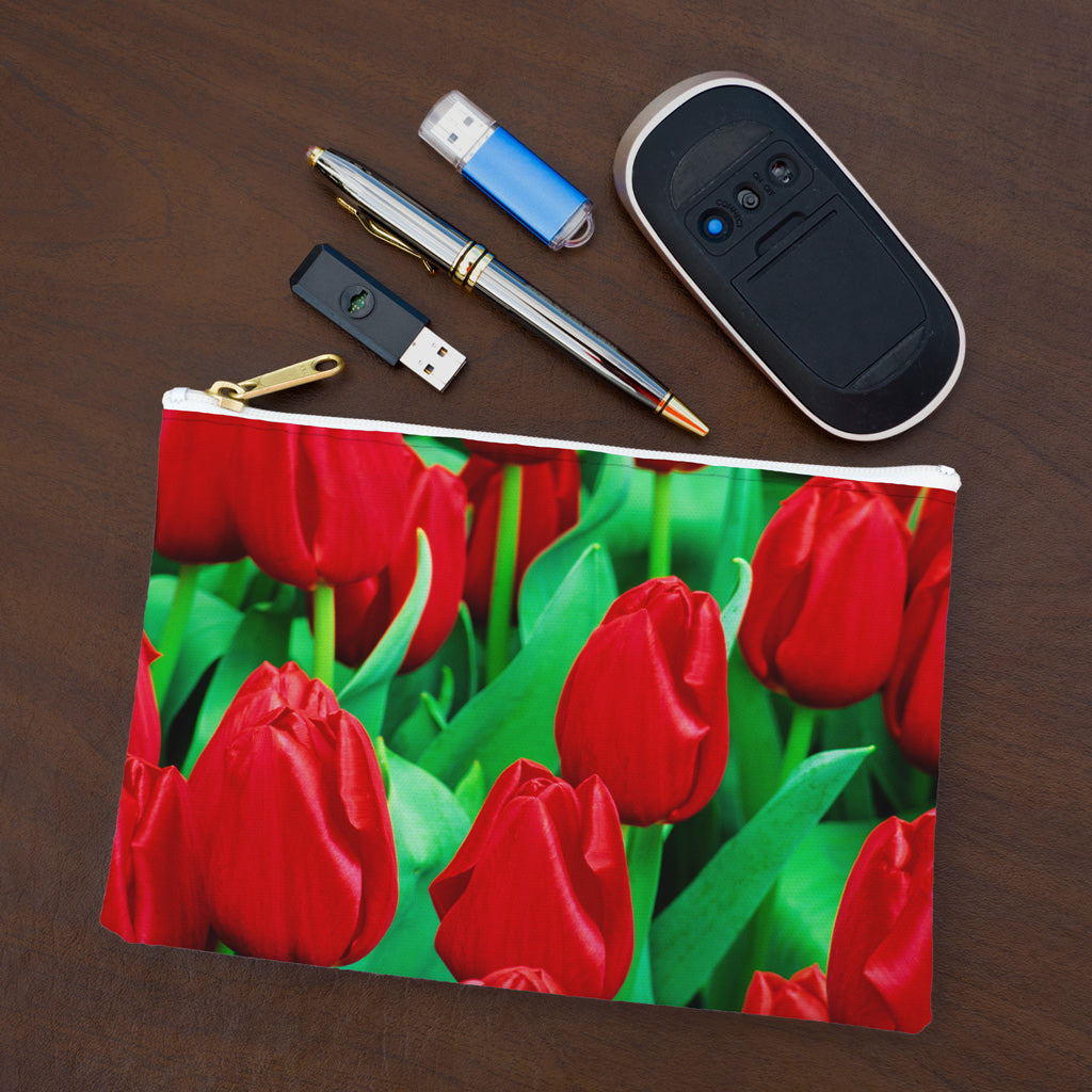 Small pouch with red tulips design lying flat on desktop with thumb drives, computer mouse and pen.