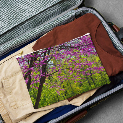 Large pouch with tree blossoms design lying flat atop the contents of an open suitcase.