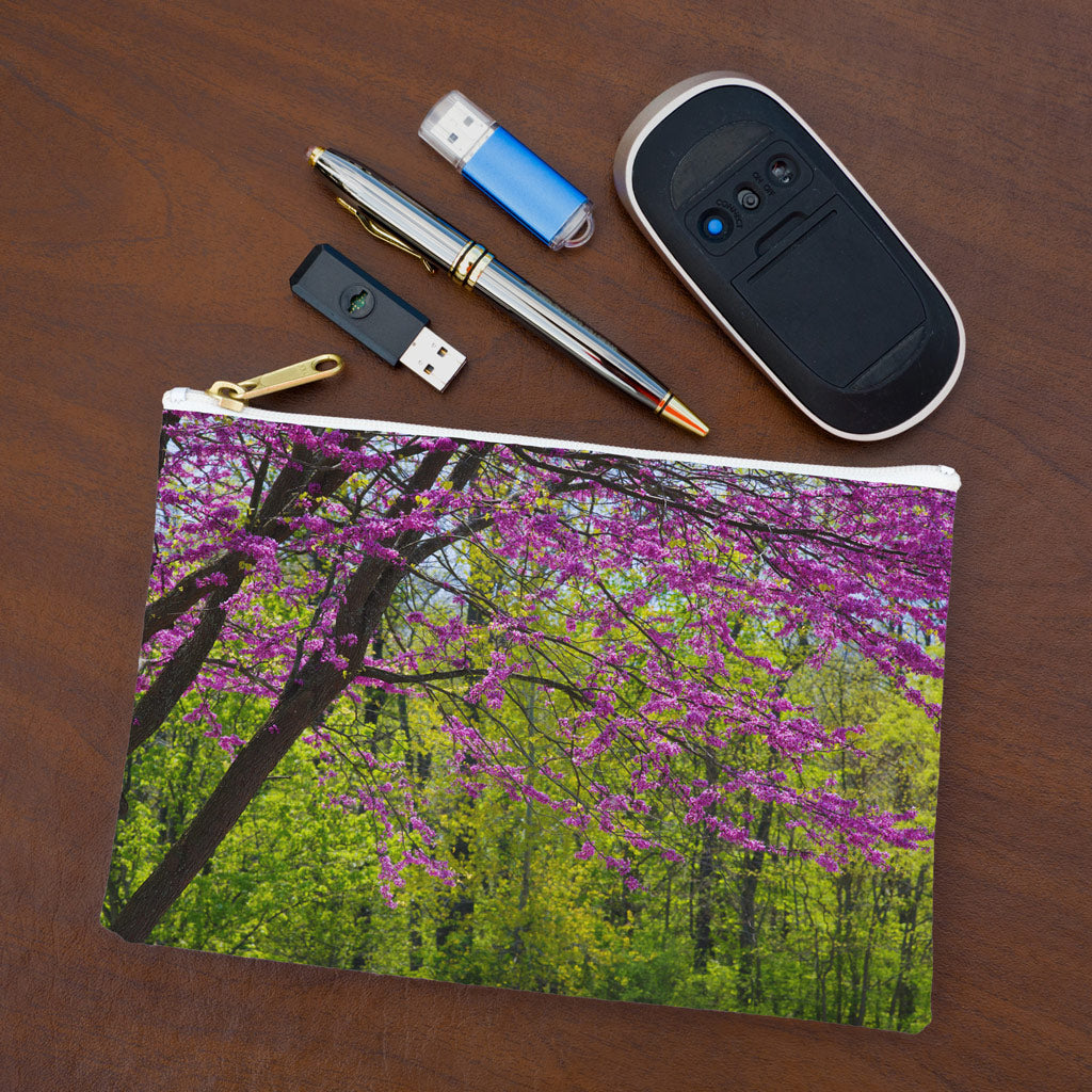 Small pouch with tree blossoms design lying flat on desktop with thumb drives, computer mouse and pen.