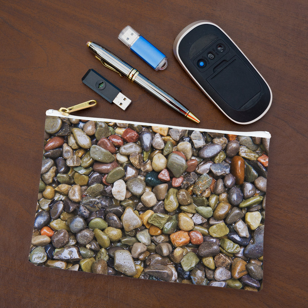 Small pouch with pebbles and stones design lying flat on desktop with thumb drives, computer mouse and pen.