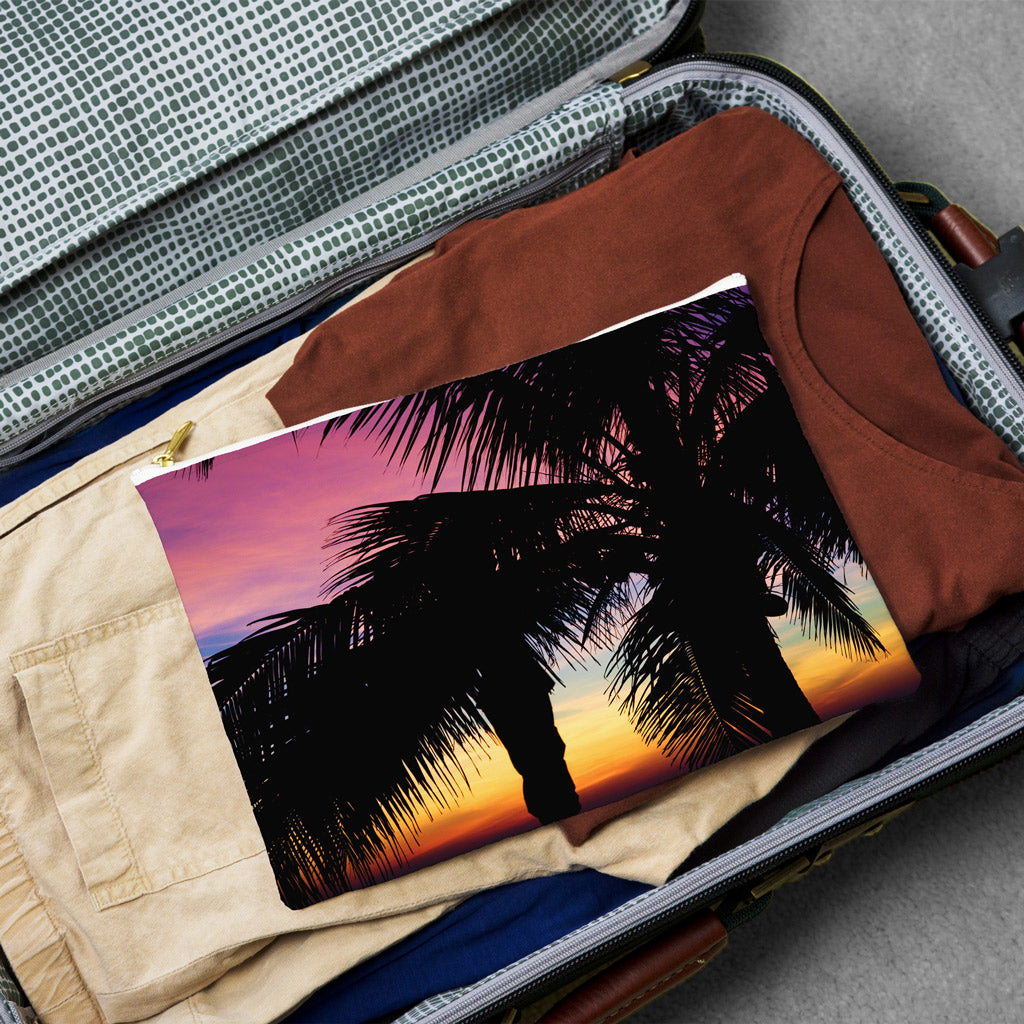 Large pouch with intense sunset design lying flat atop the contents of an open suitcase.