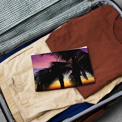 Small pouch with intense sunset design lying flat atop the contents of an open suitcase.