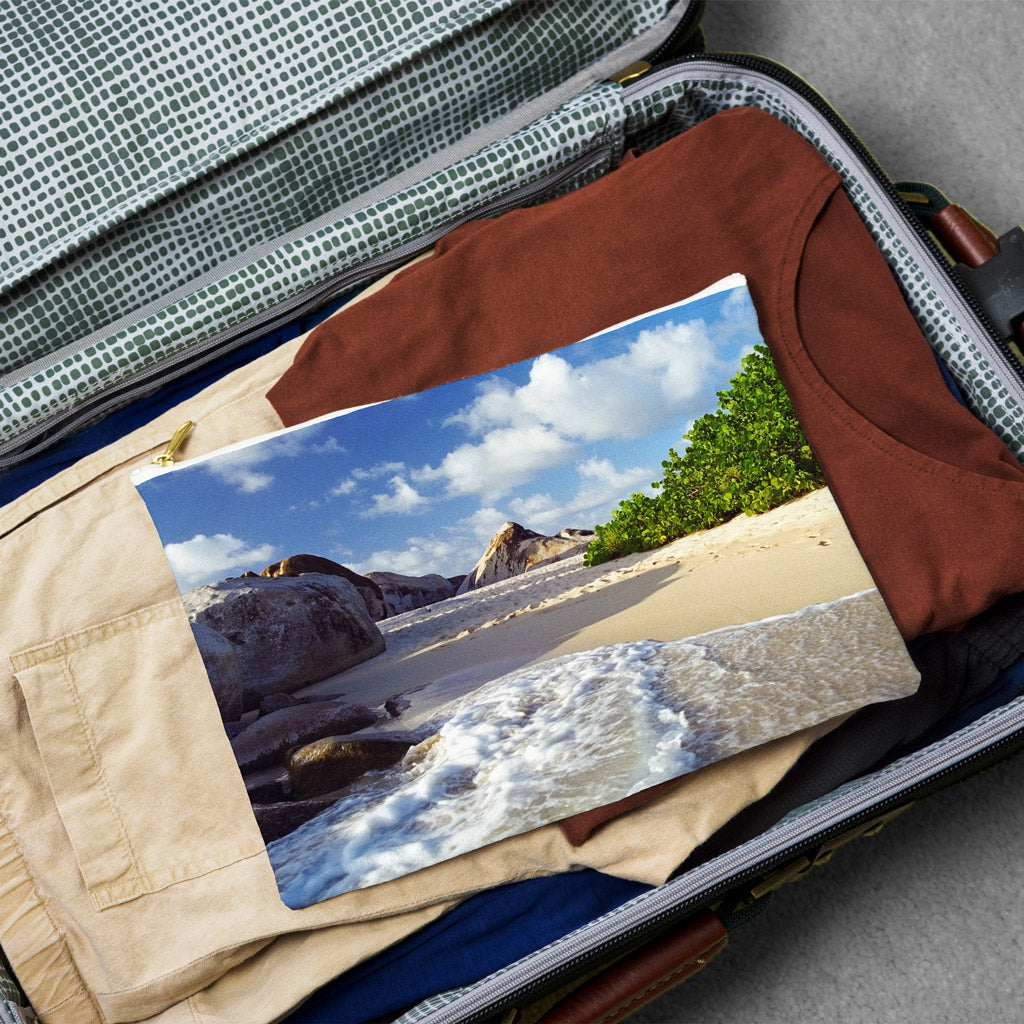 Large pouch with beach surf design lying flat atop the contents of an open suitcase.