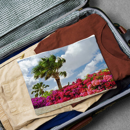 Large pouch with tropical flowers design lying flat atop the contents of an open suitcase.