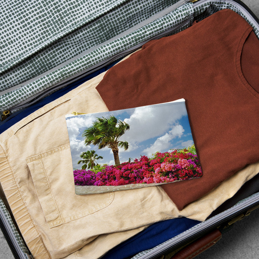 Small pouch with tropical flowers design lying flat atop the contents of an open suitcase.