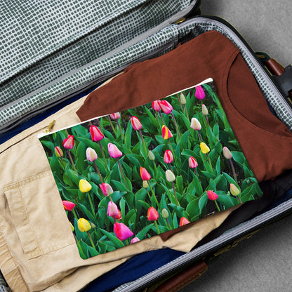 Large pouch with multi colored tulips design lying flat atop the contents of an open suitcase.