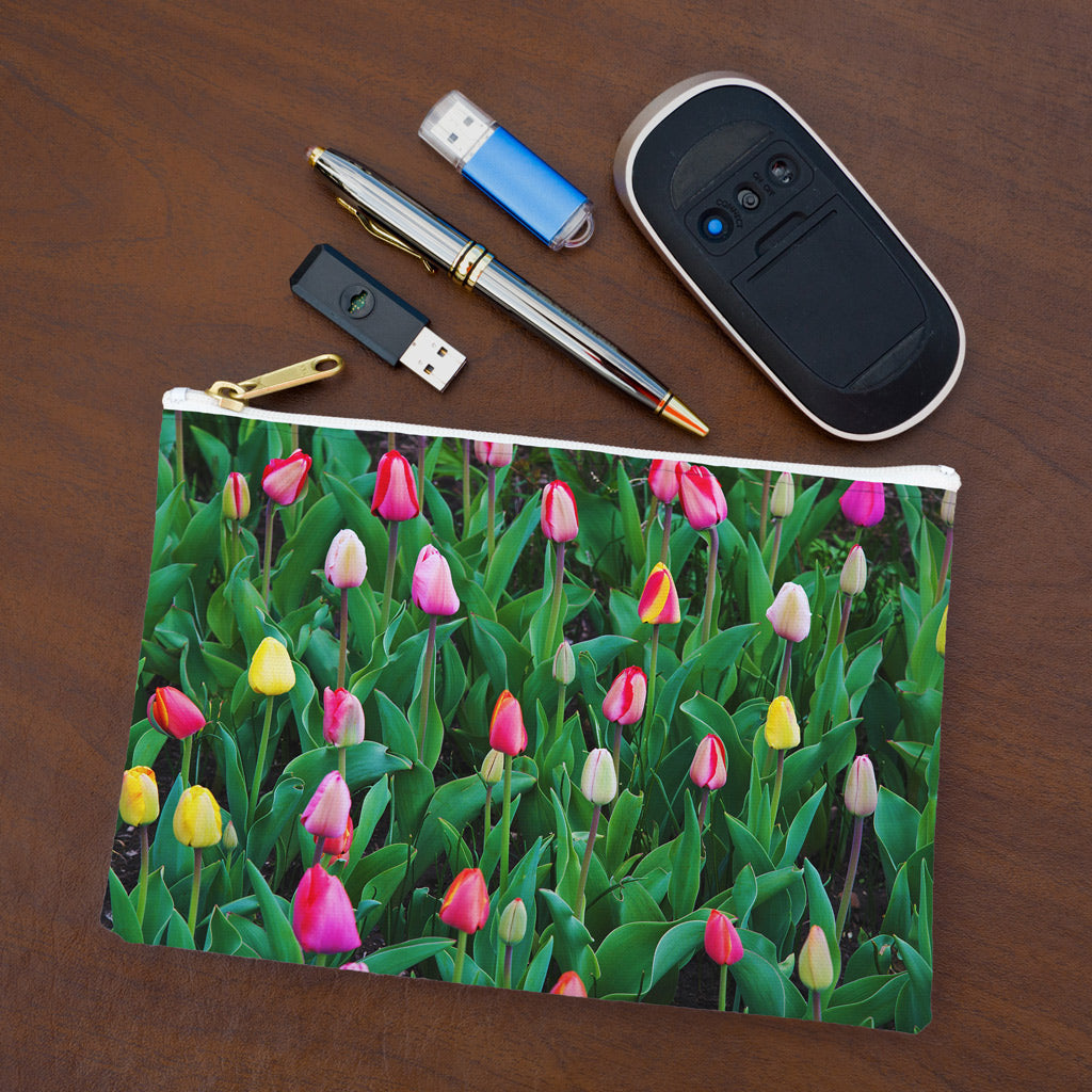 Small pouch with multi colored tulips design lying flat on desktop with thumb drives, computer mouse and pen.