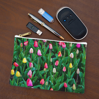 Small pouch with multi colored tulips design lying flat on desktop with thumb drives, computer mouse and pen.