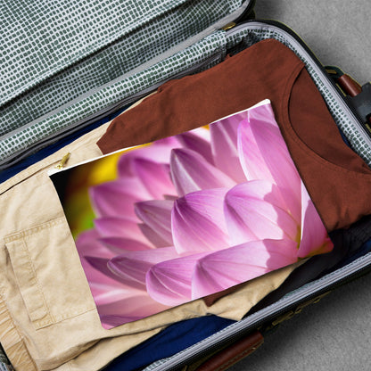 Large pouch with flower petals design lying flat atop the contents of an open suitcase.