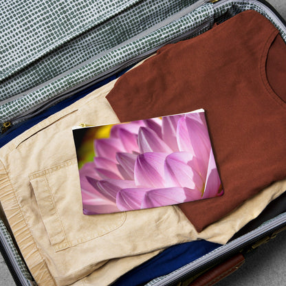 Small pouch with flower petals design lying flat atop the contents of an open suitcase.