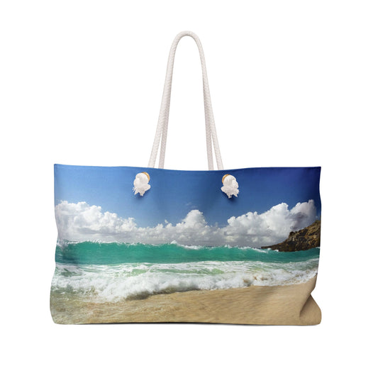 Front view of a beach bag featuring vibrant photo art of a vast turquoise Caribbean wave cresting about to crash on the beach.
