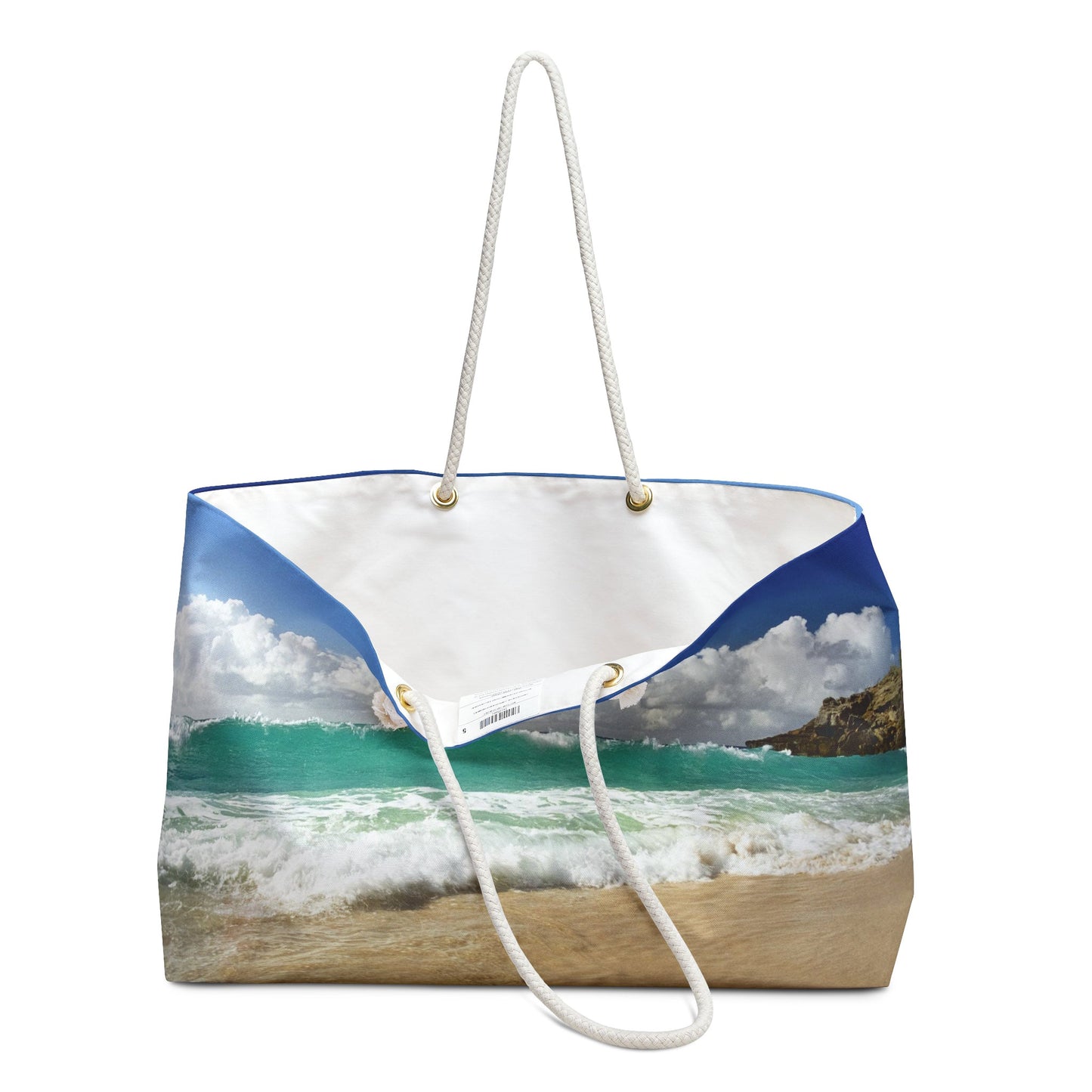 An open view of the beach bag with crashing waves design shows the cream colored interior lining.