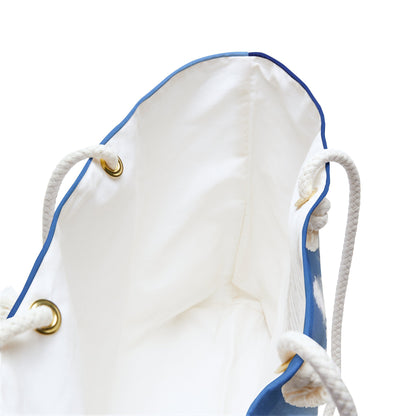 A close up view of the beach bag with crashing waves design shows the braided rope handles with metal grommets.