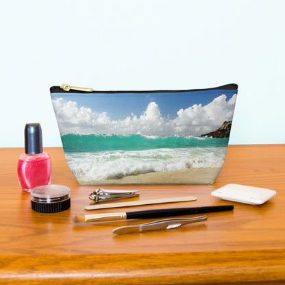 Kit bag with crashing waves design next to nail polish, tweezers, nail clippers, makeup brush, blush and eye shadow.