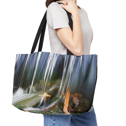 Young woman with a weekender bag featuring the creek waterfall design hanging from her shoulder.