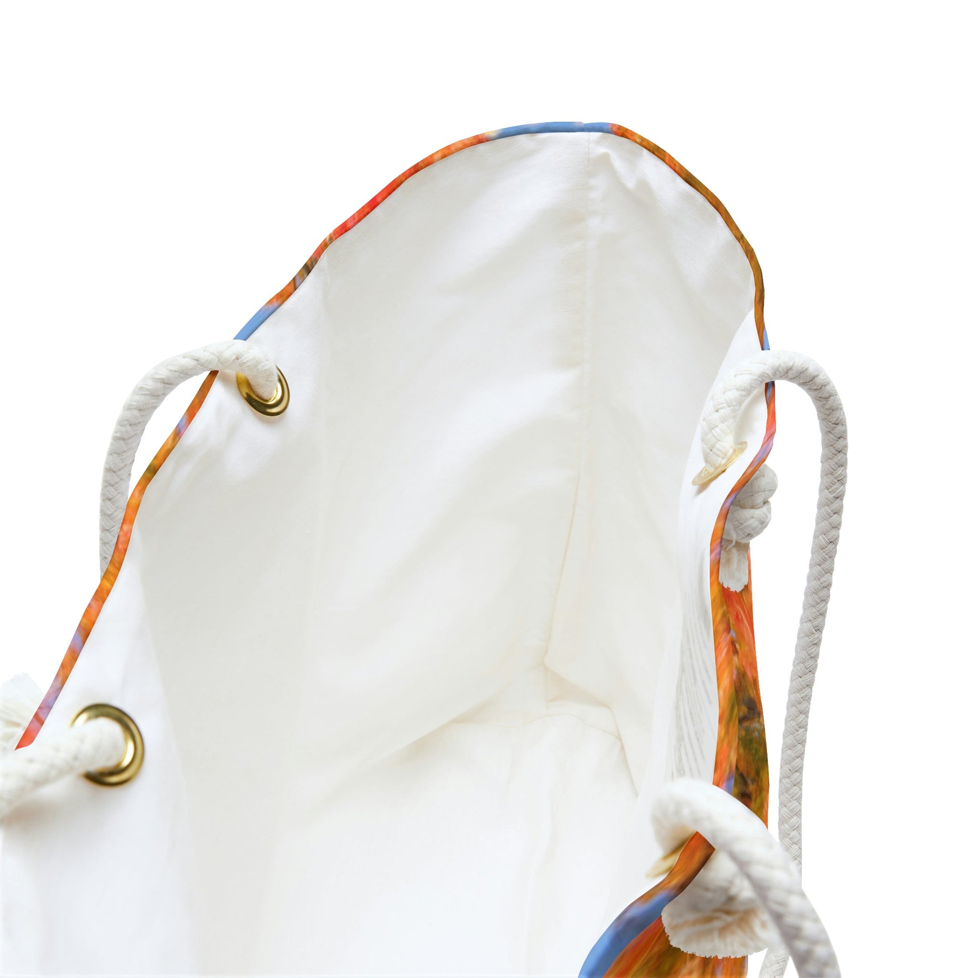 A close up view of the beach bag with fall colored trees design shows the braided rope handles with metal grommets.