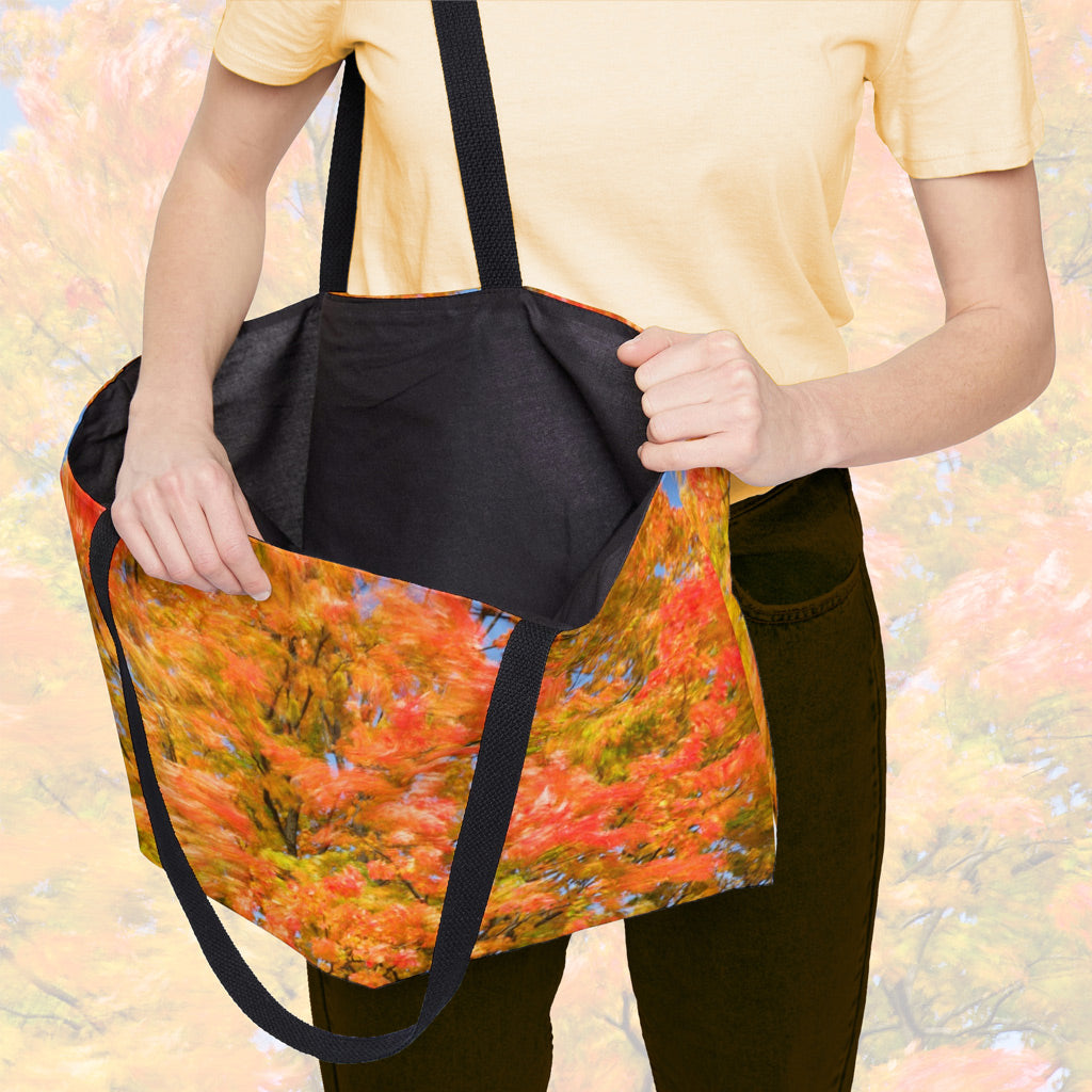 A woman holding open a weekender bag featuring the fall colored trees design, showcasing the roomy interior.