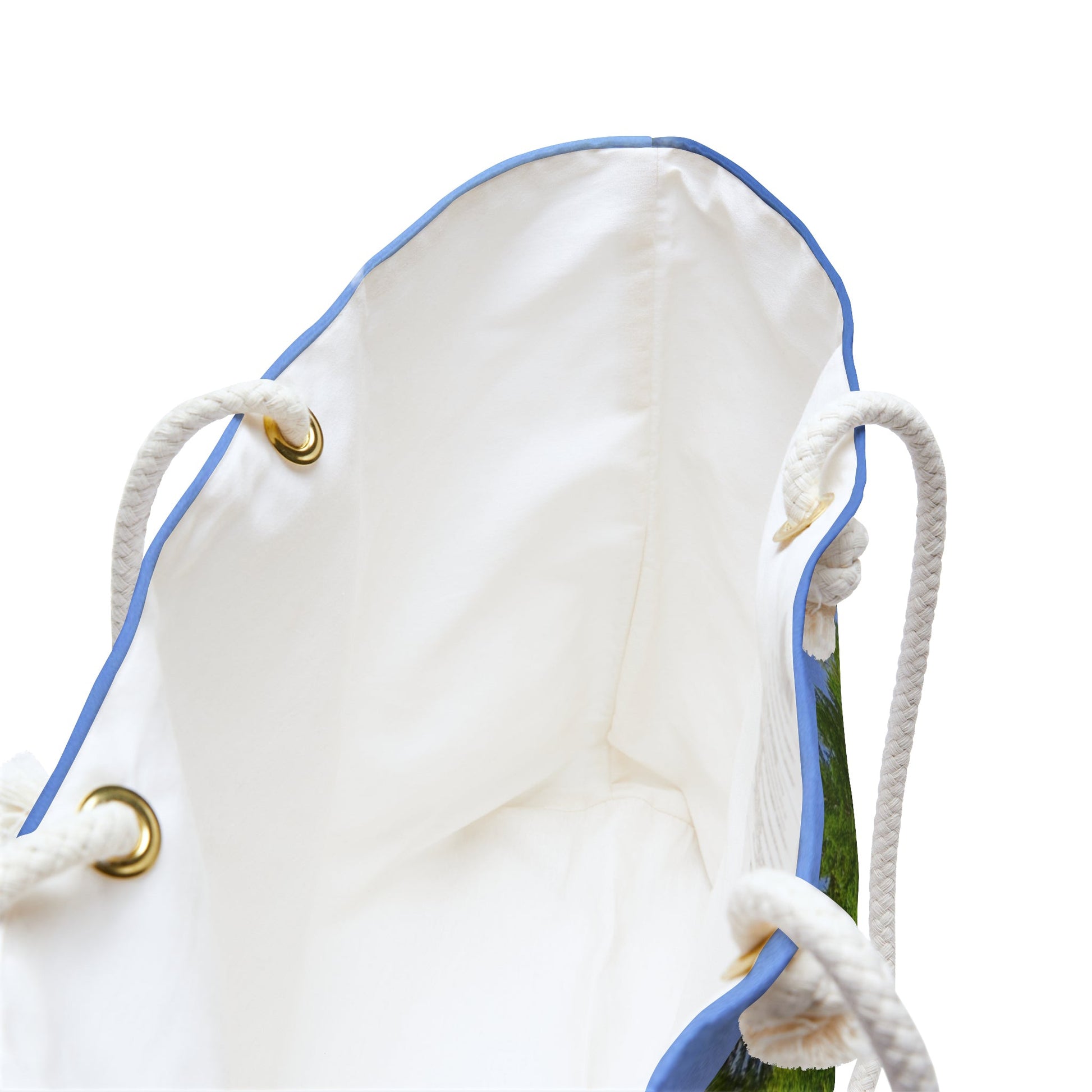 A close up view of the beach bag with forest waterfall design shows the braided rope handles with metal grommets.