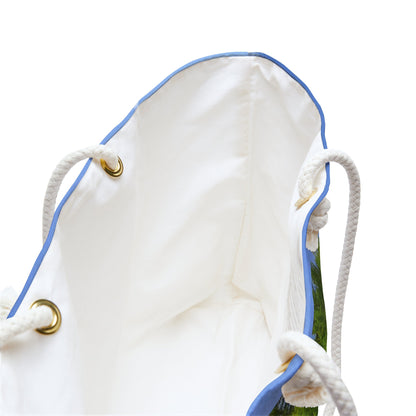 A close up view of the beach bag with forest waterfall design shows the braided rope handles with metal grommets.