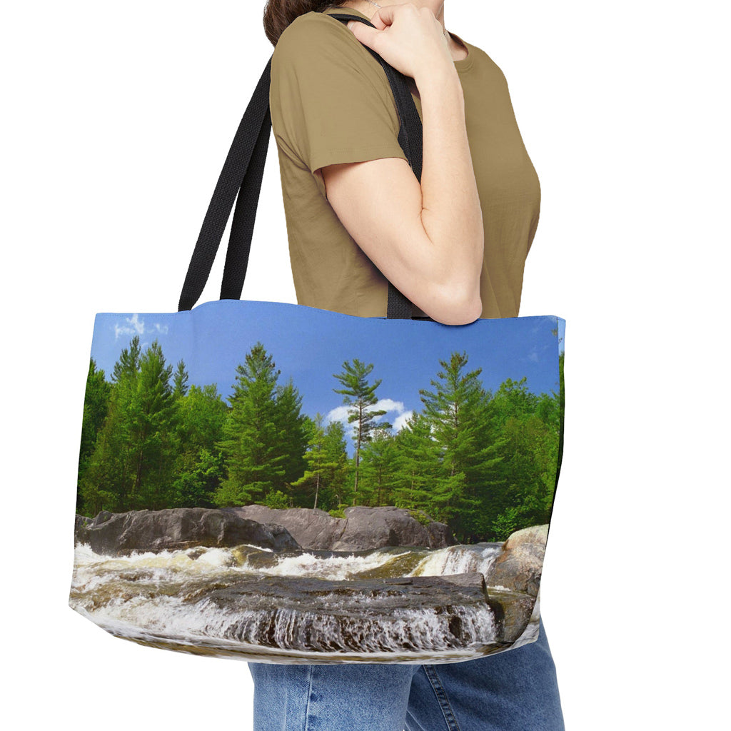 Young woman with a weekender bag featuring the forest waterfall design hanging from her shoulder.