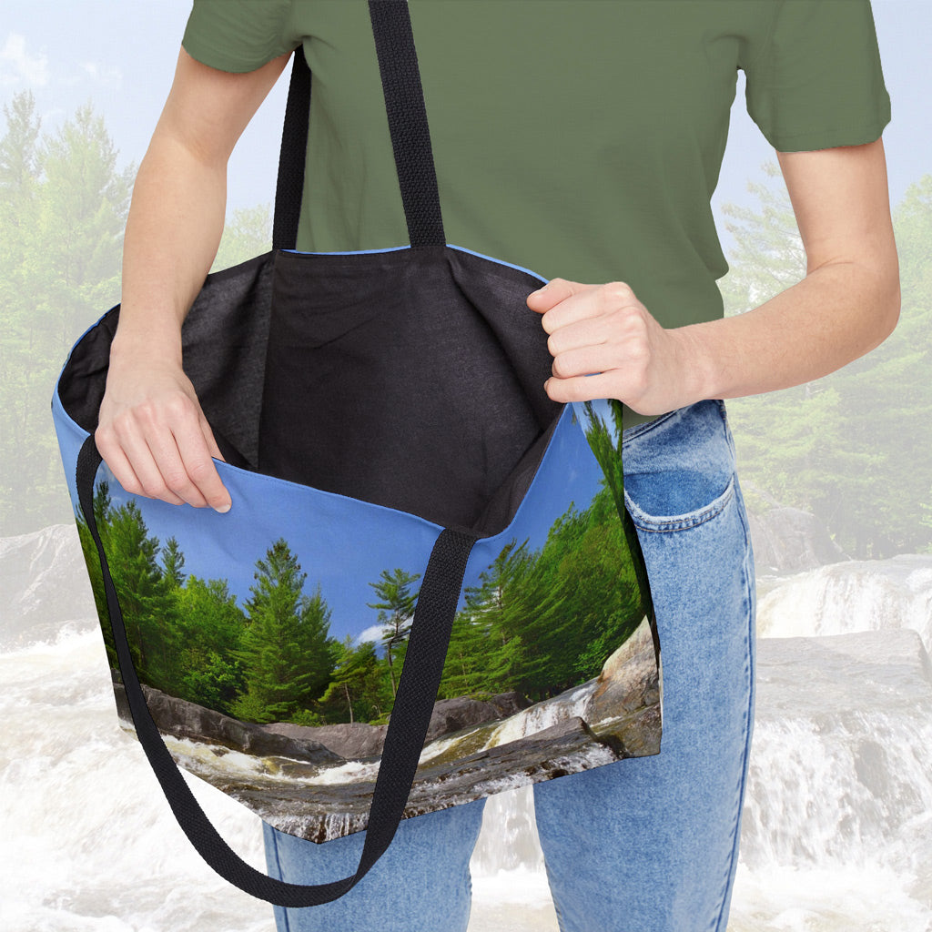 A woman holding open a weekender bag featuring the forest waterfall design, showcasing the roomy interior.