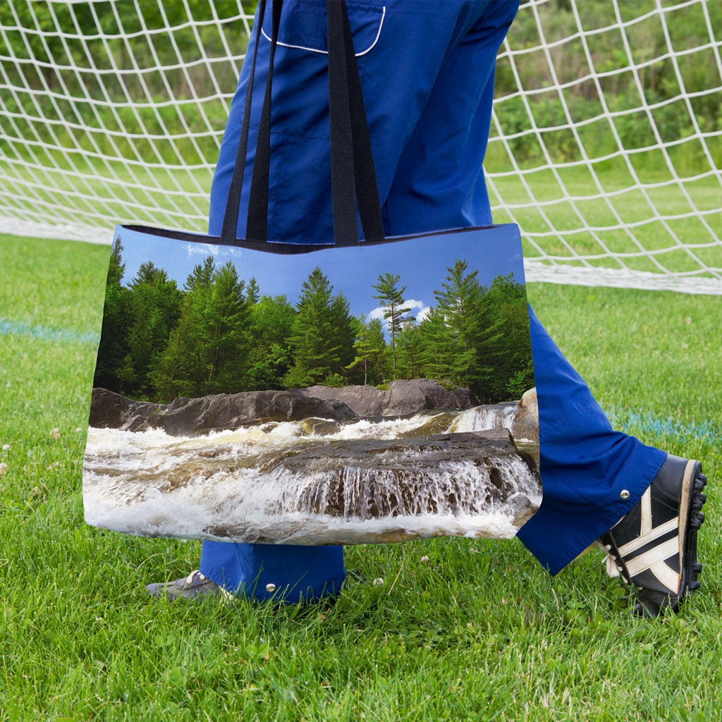 A soccer player carrying a weekender bag featuring the forest waterfall design onto the practice field.