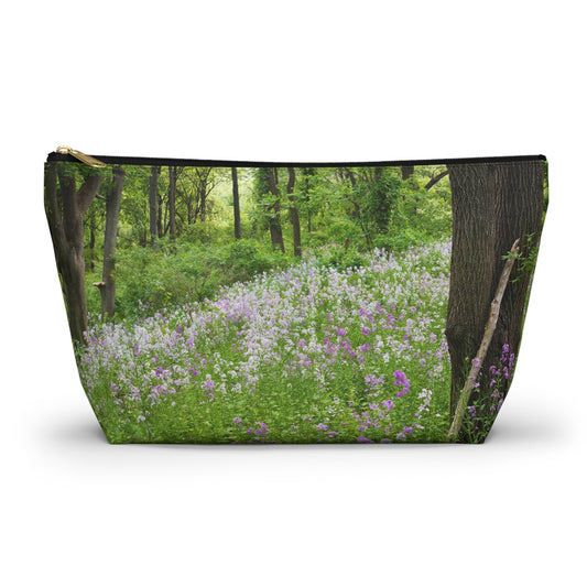 Zippered accessory pouch featuring vibrant photo art of a forest hillside filled with lilac colored wildflowers.