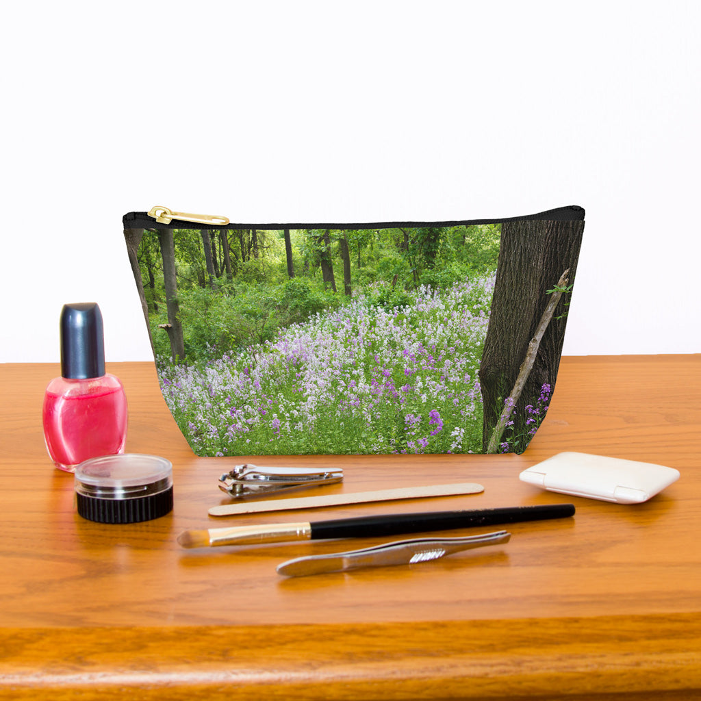 Kit bag with forest wildflowers design next to nail polish, tweezers, nail clippers, makeup brush, blush and eye shadow.