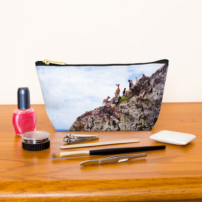 Kit bag with curious goats design next to nail polish, tweezers, nail clippers, makeup brush, blush and eye shadow.