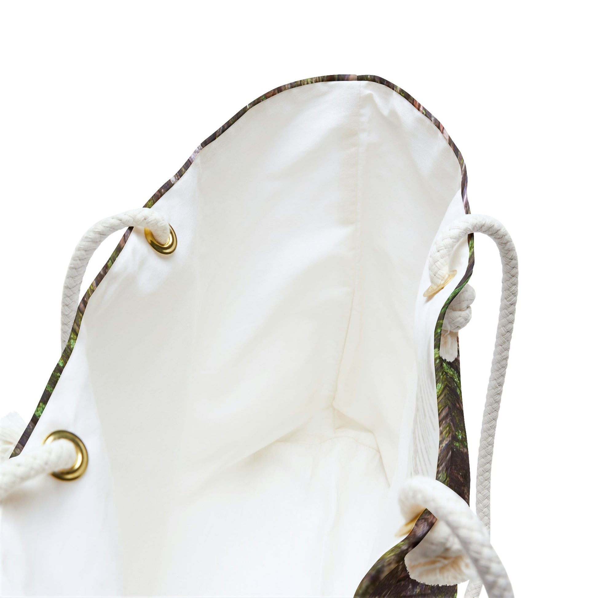A close up view of the beach bag with green mossy bark design shows the braided rope handles with metal grommets.