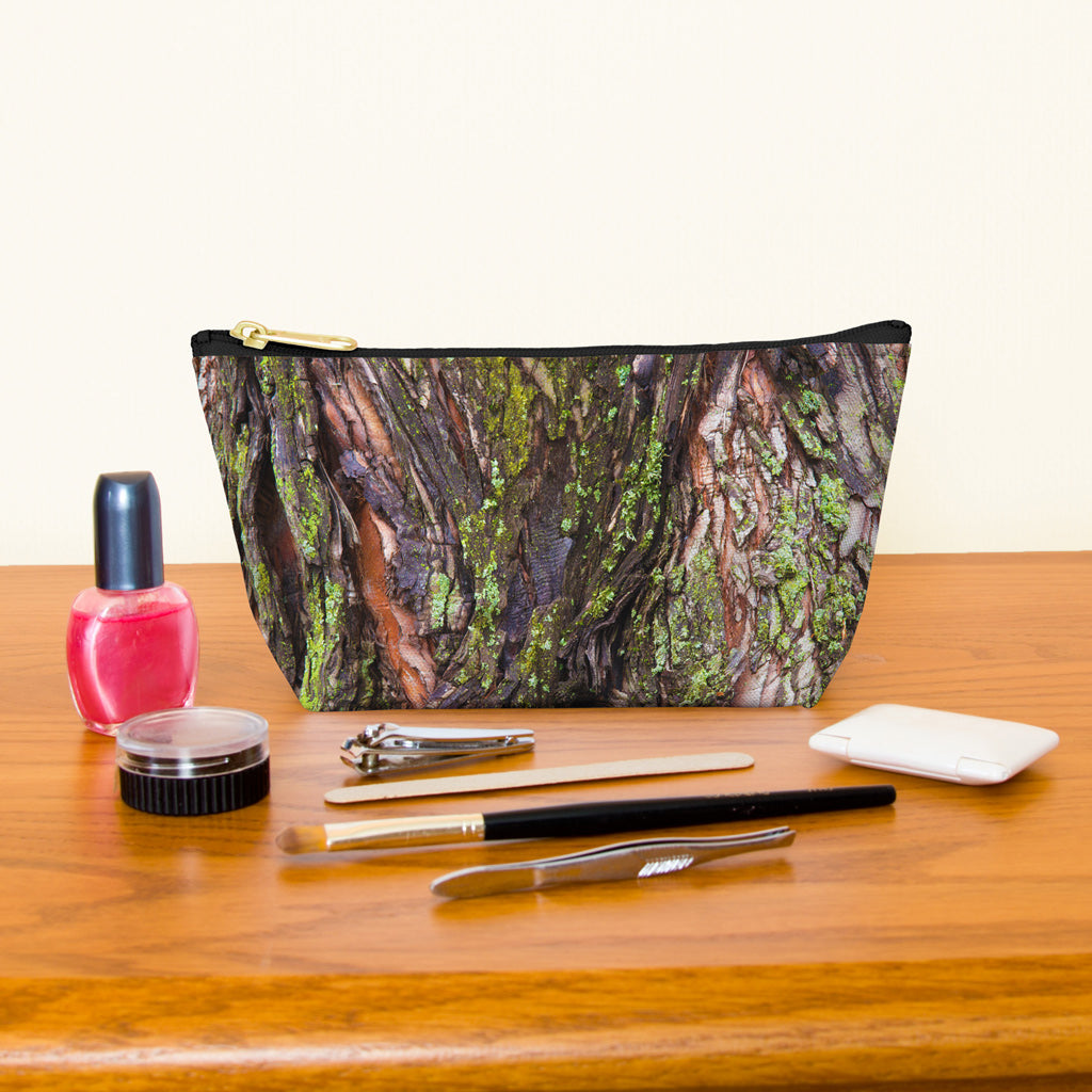 Kit bag with green mossy bark design next to nail polish, tweezers, nail clippers, makeup brush, blush and eye shadow.