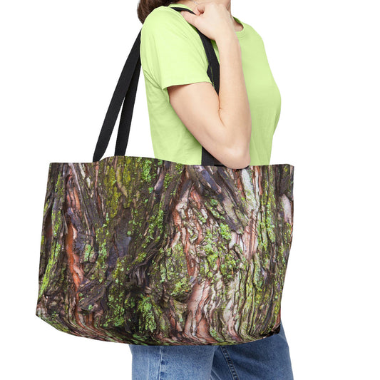 Young woman with a weekender bag featuring the green mossy bark design hanging from her shoulder.