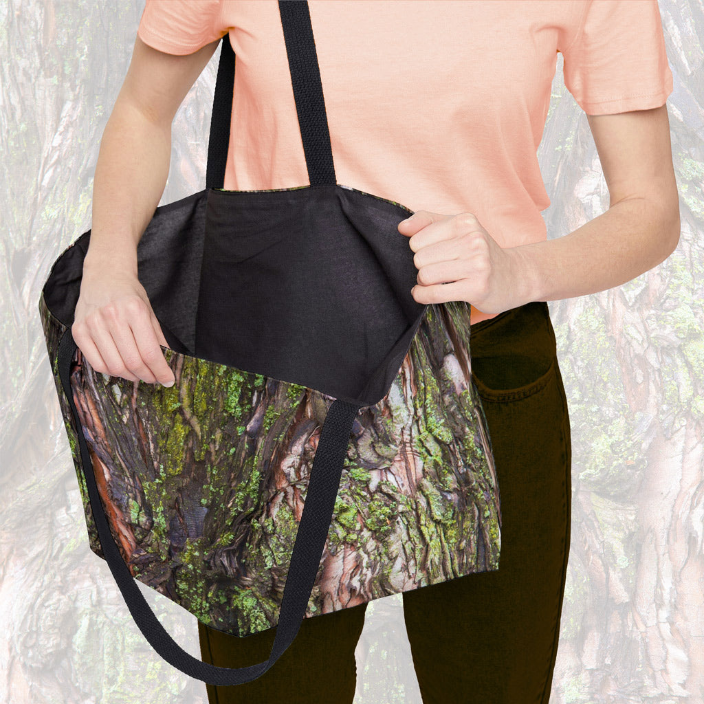 A woman holding open a weekender bag featuring the green mossy bark design, showcasing the roomy interior.