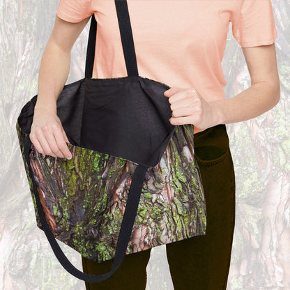 A woman holding open a weekender bag featuring the green mossy bark design, showcasing the roomy interior.