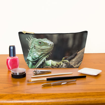 Kit bag with green iguana design next to nail polish, tweezers, nail clippers, makeup brush, blush and eye shadow.