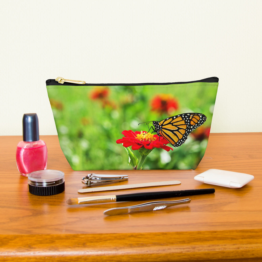 Kit bag with butterfly on flower design next to nail polish, tweezers, nail clippers, makeup brush, blush and eye shadow.