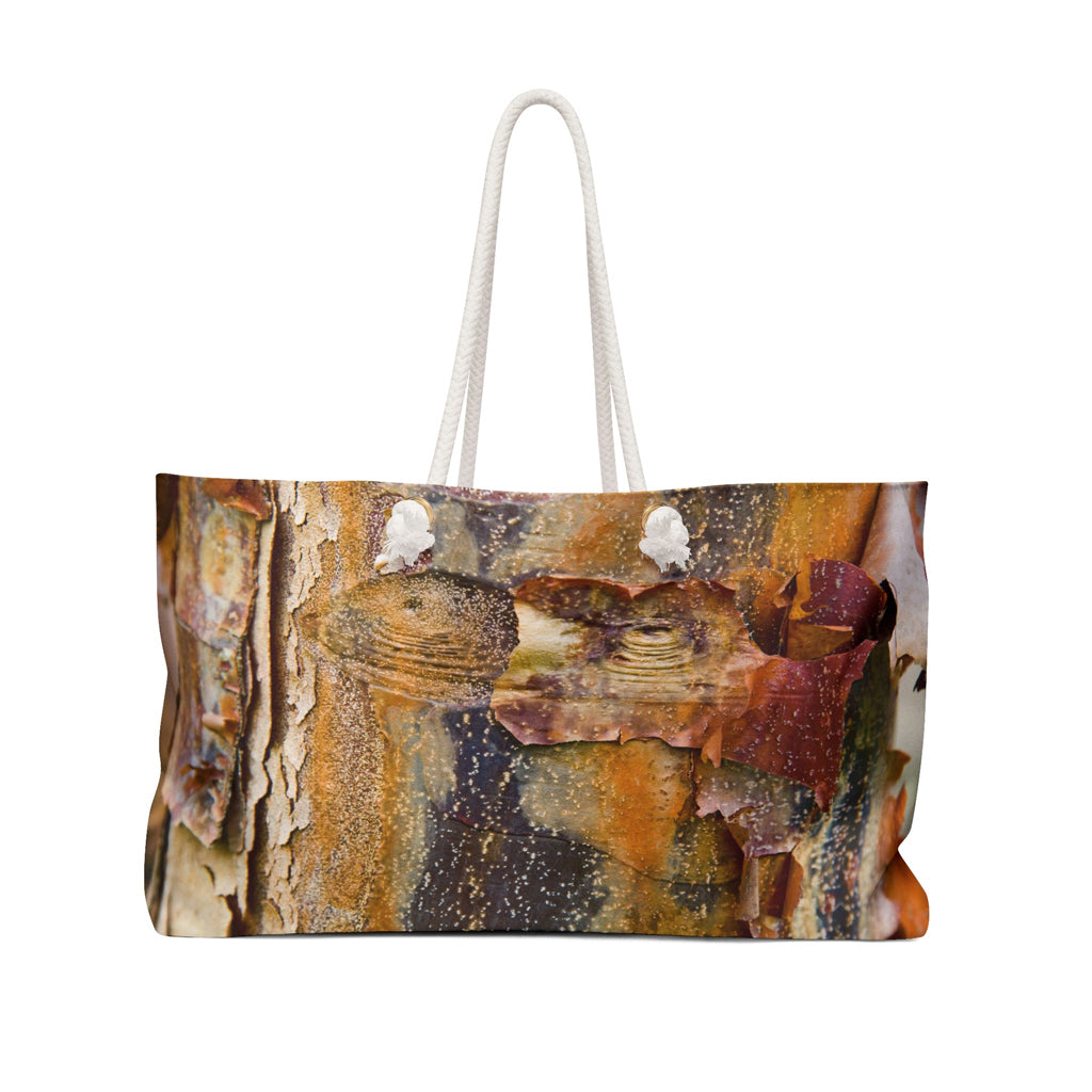 Front view of a beach bag featuring vibrant photo art of orange tree bark with eyes and sly smile facial features.